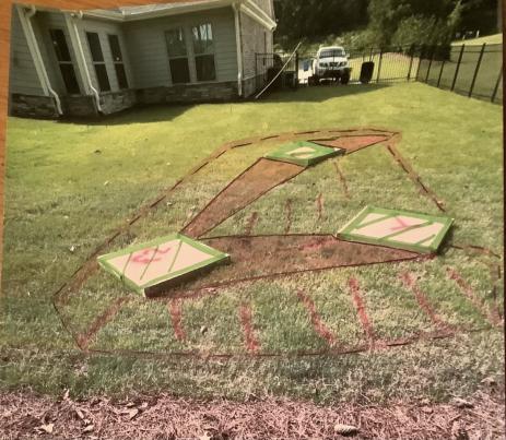 Cardboard boxes and turf marking paint help visualize the future location of the crevice garden.